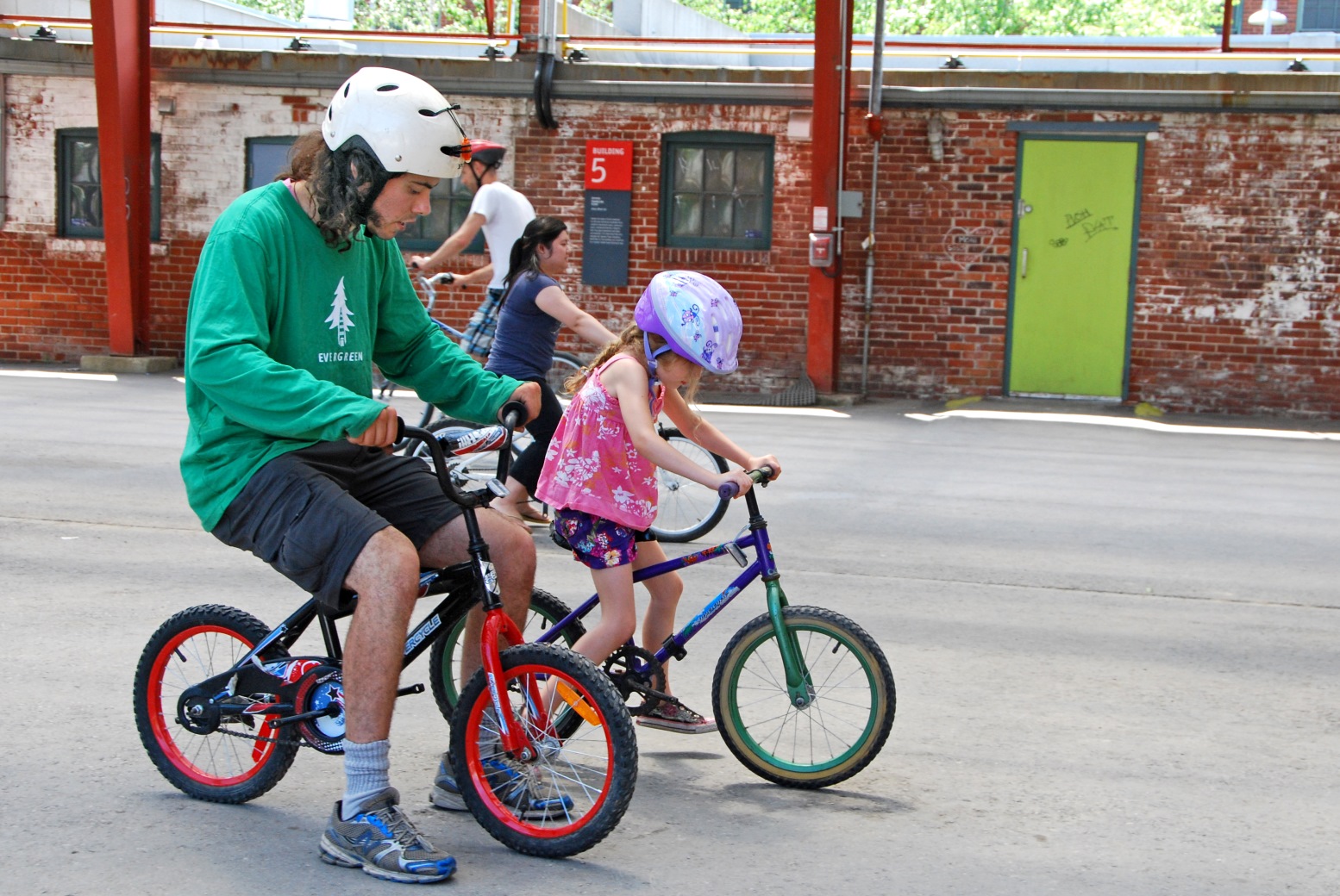 Man teach young child how to use a bicycle at Evergreen Brick Works
