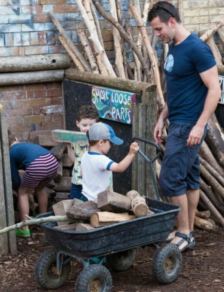 Man and kids gathering pieces of wood in a wagon