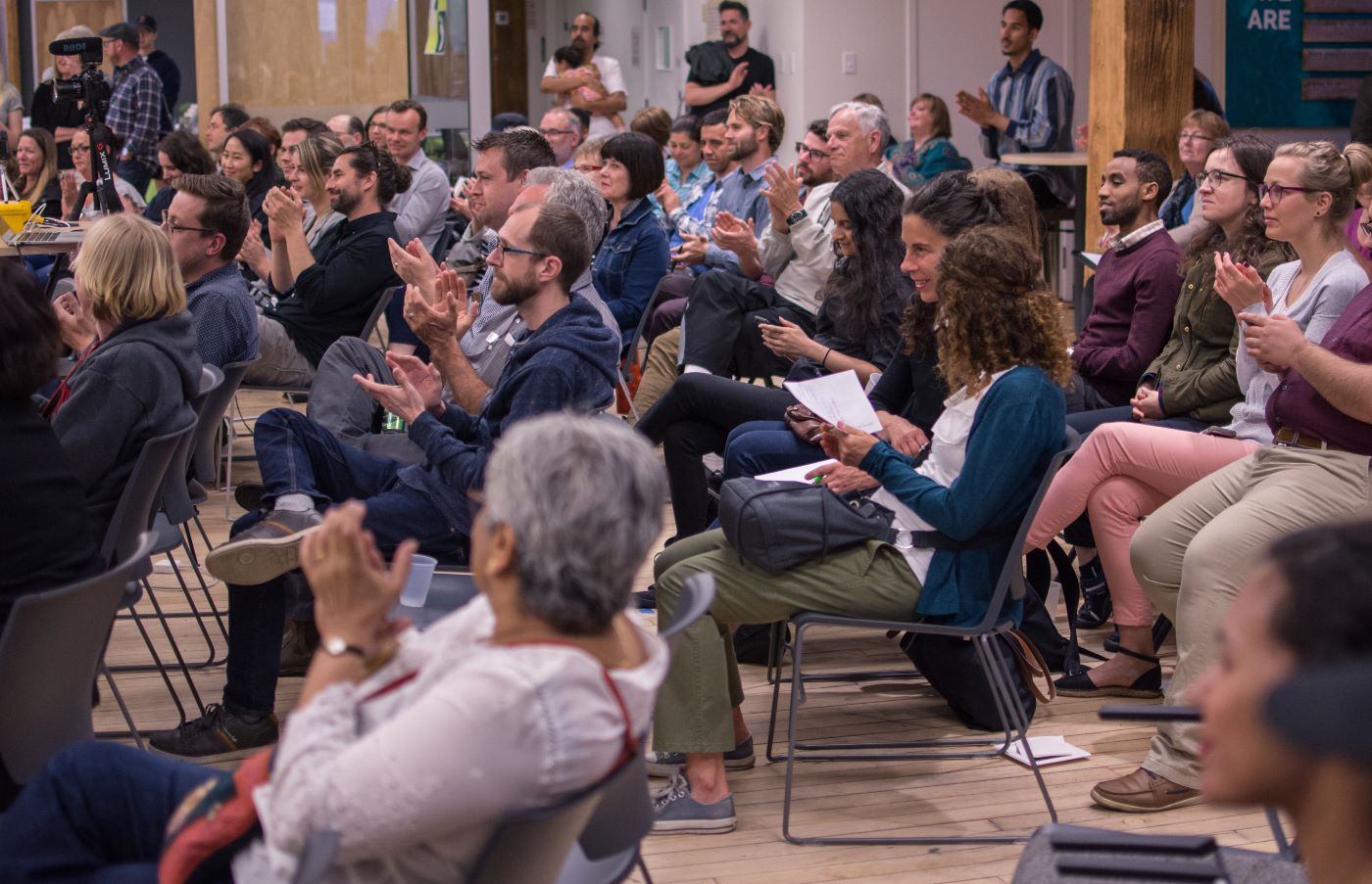 Group of people clapping at a community forum