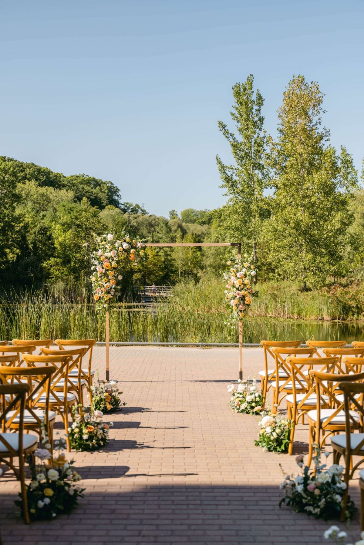 Evergreen Brickworks summer outdoor wedding against pond and florest with closeup of arbour/arch with florals.