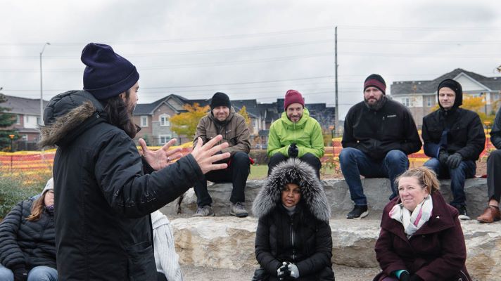 Agroup of adult sitting on outdoor amphitheater listening to a speaker