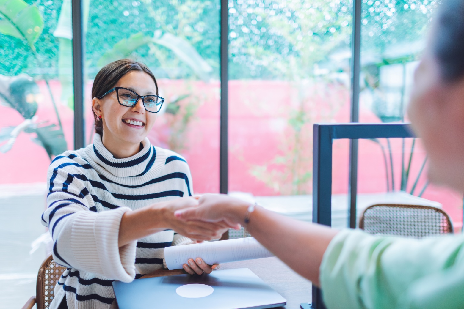 Two women shaking hands in the workplace.