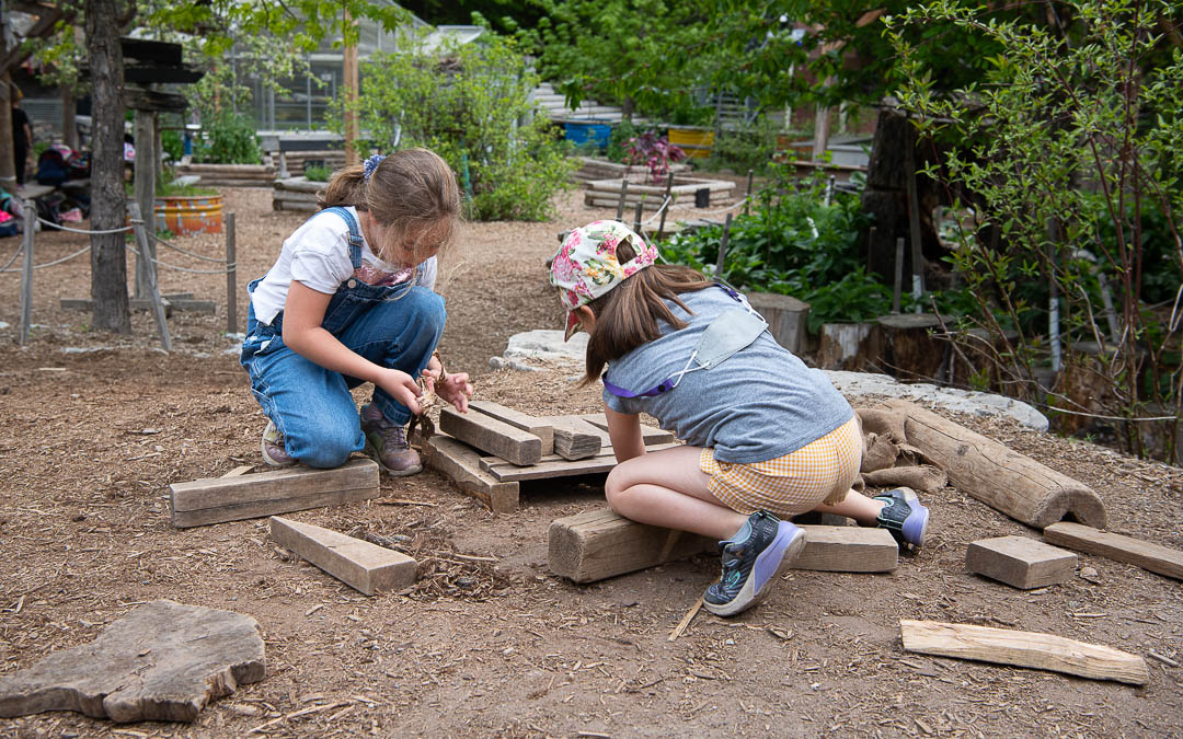 Children play with natural wooden blocks on the ground in the Children's Garden at Evergreen Brick Works