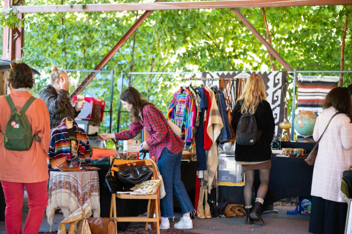 Women shopping for clothes at an outdoor market.