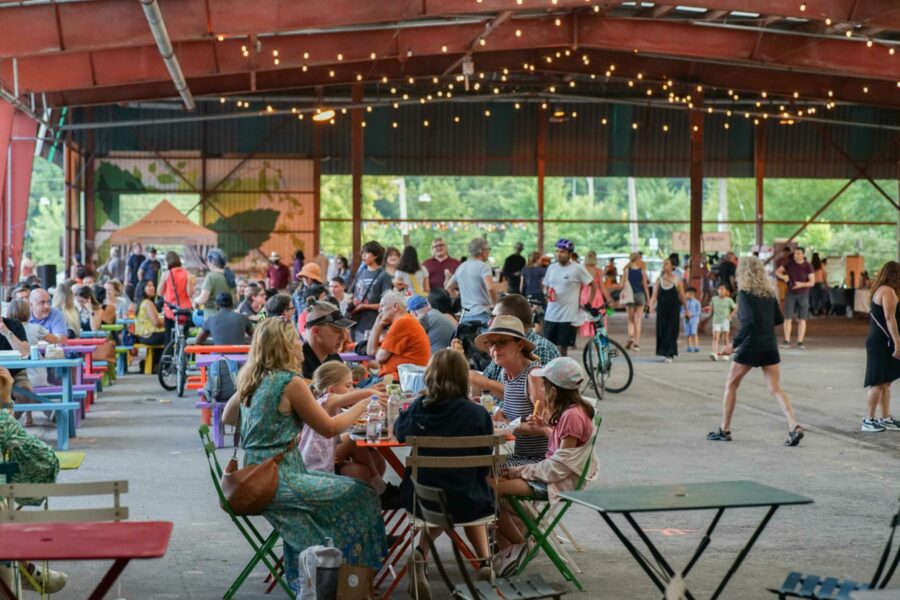 Group of people in covered outdoor area sharing food.