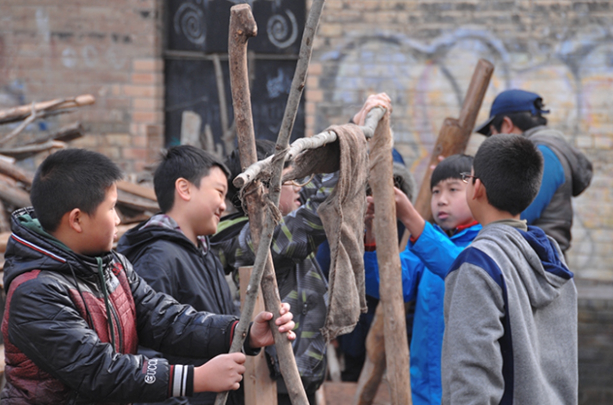 Group of high school boys creating a craft ourdoors
