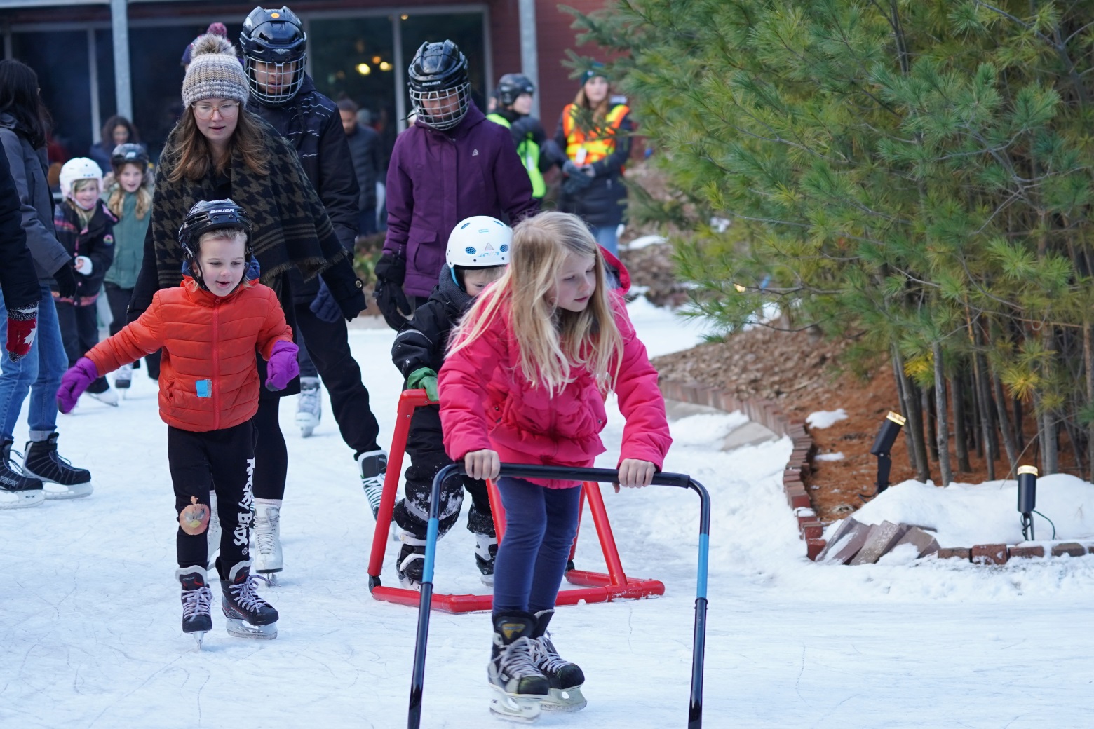 Children and adults skating on an outdoor rink.