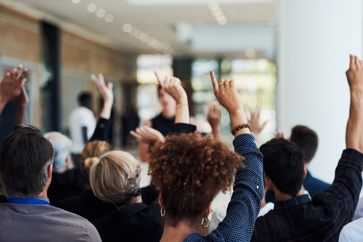 Group of people raising hands to ask questions
