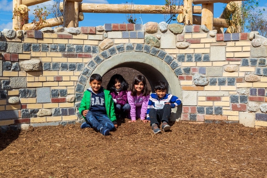 Kids sit under a small bridge in ttheir playground