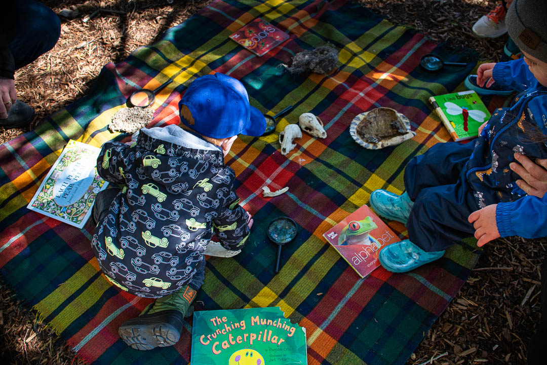 A child playing with nature items on a picnic blanket at Evergreen Brick Works