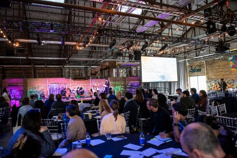 Des personnes assises à des tables écoutent un panel sur scène lors de la conférence Evergreen octobre 2023