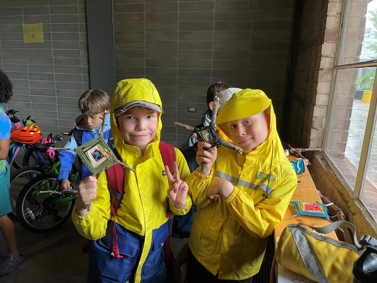 Two boys showing their stick and yarn crafts.