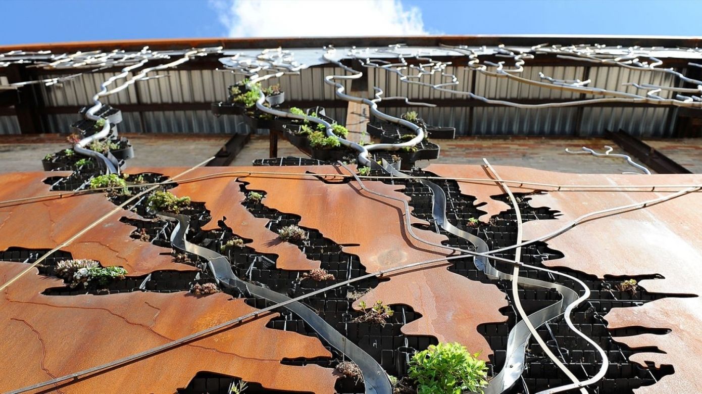 Watershed wall at Evergreen Brick Works - waterways of Toronto shown through metal pipes and metal pathways with plants.