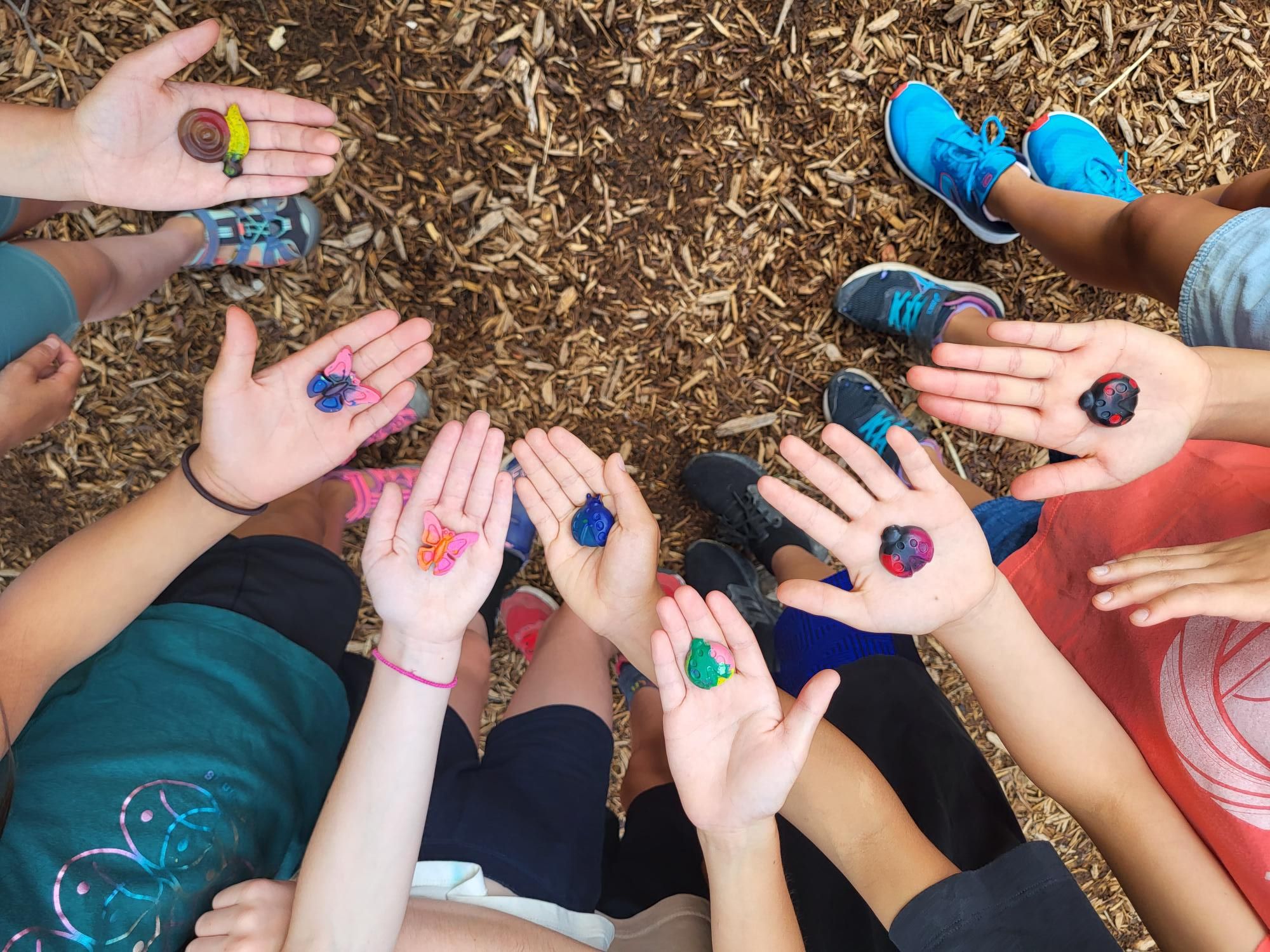 Kids showing clay insect crafts in the palms of their hands.