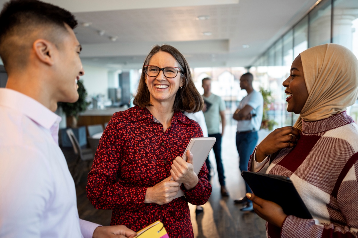 Three business people talking in an office space after a conference
