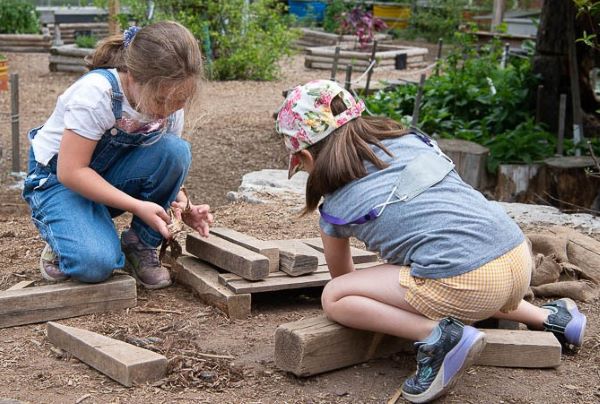 two kids are playing with wood in Evergreen Brick Works children garden