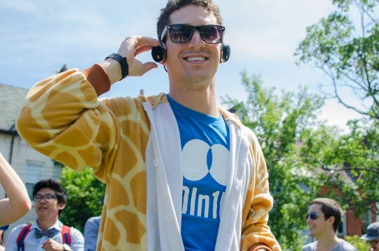 Man in Giraffe onesie with headphones on outside.