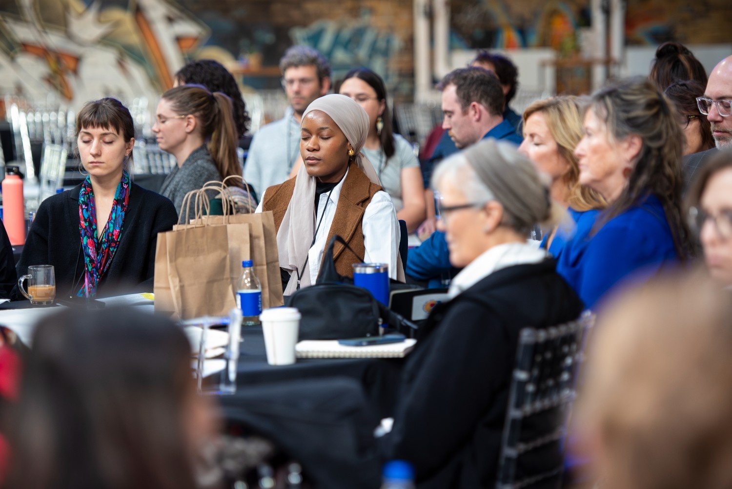 Group of people with eyes closed at a table at conference