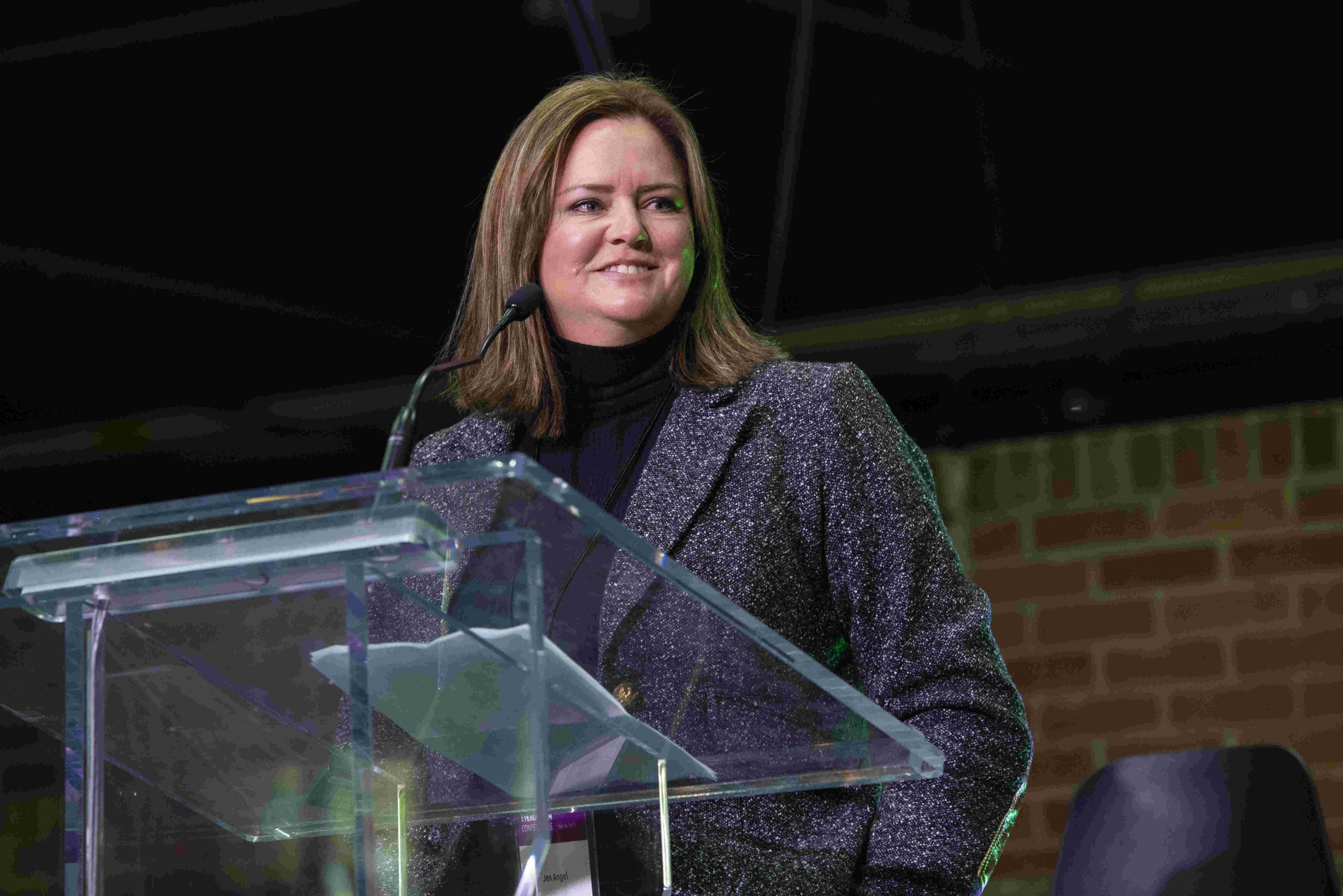 Jen Angel stands at podium speaking at conference