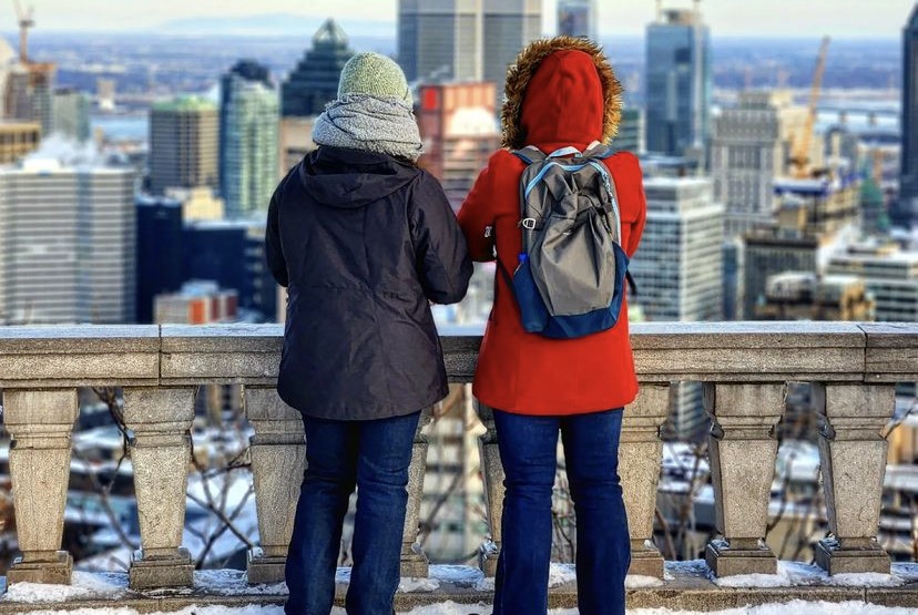 two people overlook city of montreal from park in the winter.