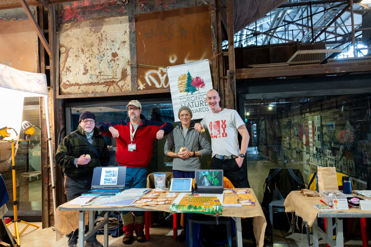 Four people pose behind a table with seeds at the Saturday Farmers Market at Evergreen Brick Works