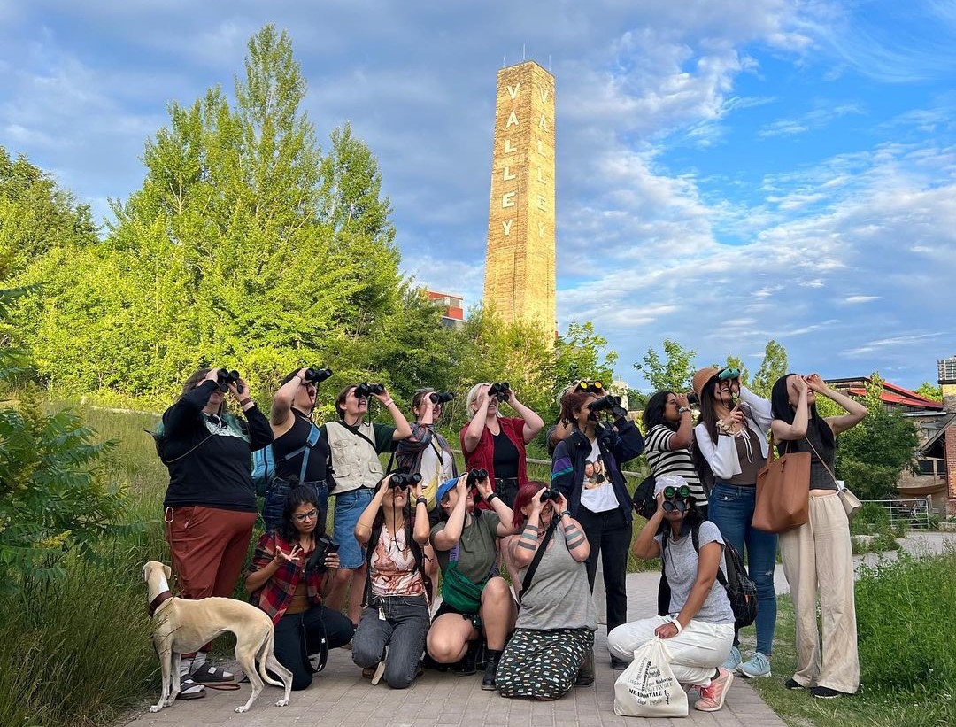 people pose with binoculars in front of evergreen brick works