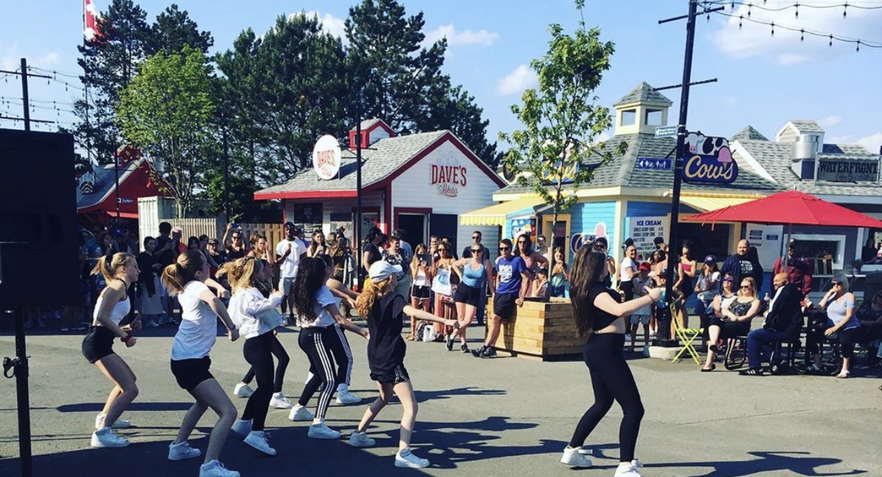 Young people perform a dance in front of crowd in public space