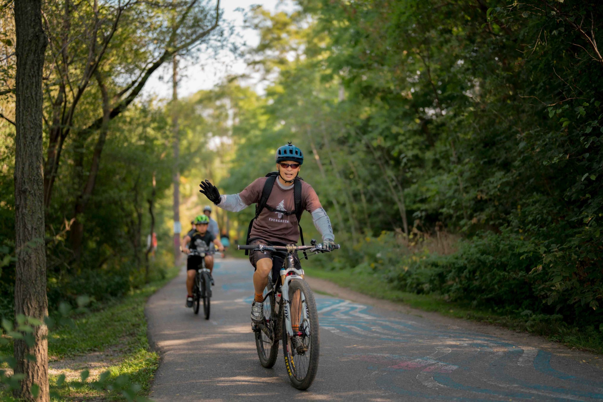 Man rides his bike in the Don Valley with his kids cycling behind him.