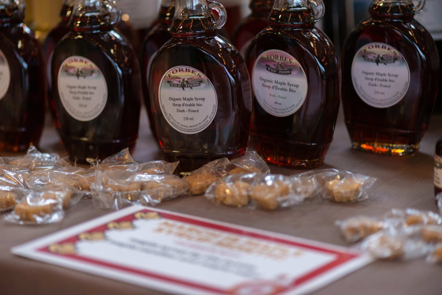 A table with maple candies and glass bottles of Forbes organic maple syrup