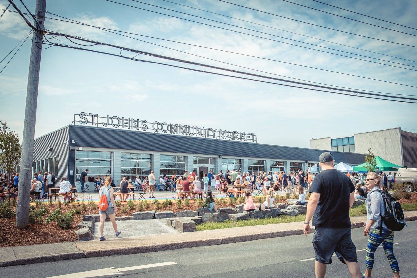 People mill around outside a market building