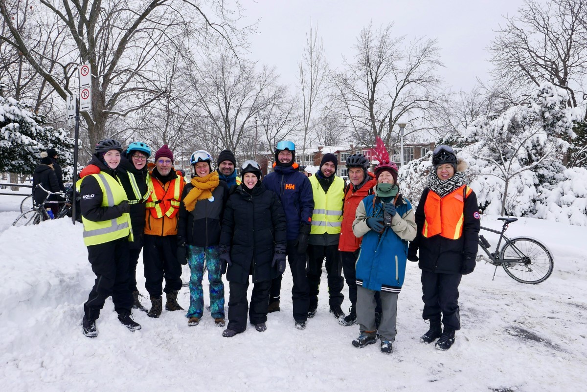 Group of people dressed up in winter outerwear with bicycles smiling at camera.