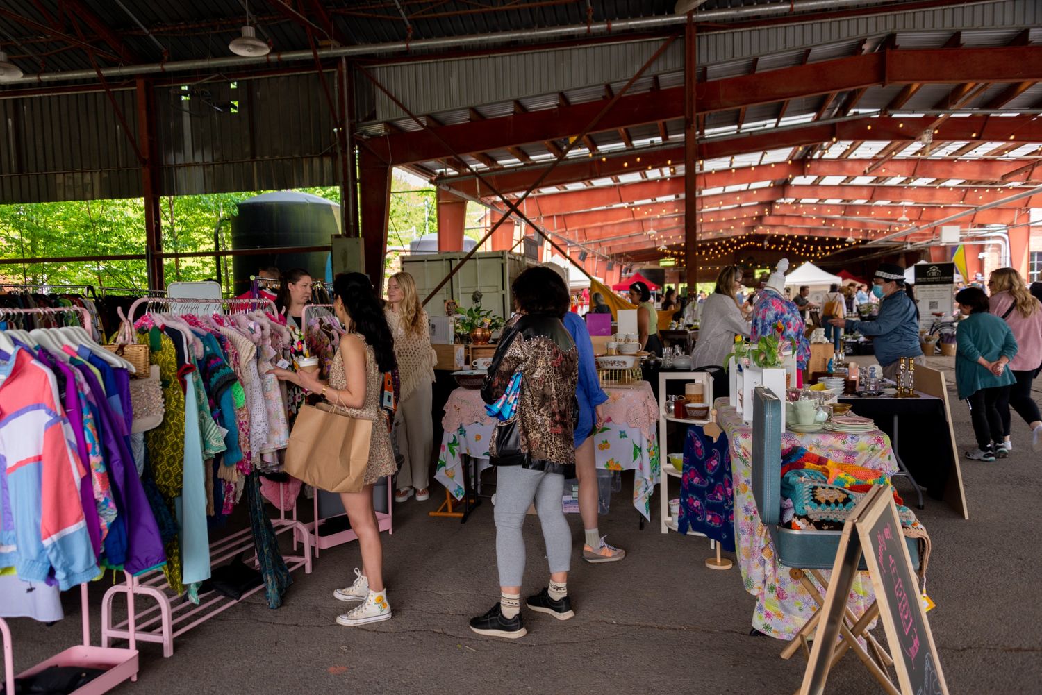 People browse through racks of vintage clothing under the twinkling lights of the pavilions at the Brick Works in spring