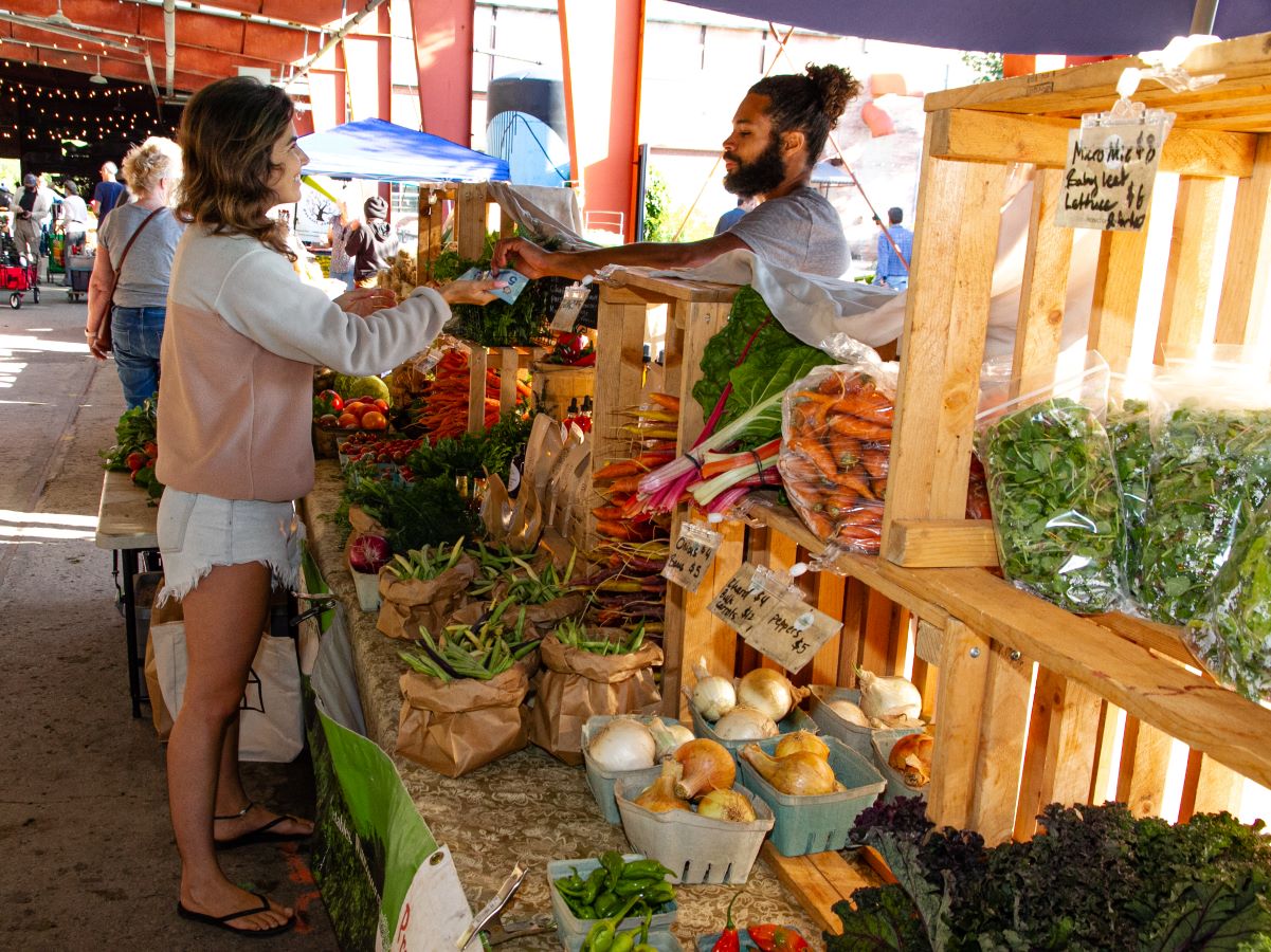 Une femme achète des produits locaux au marché fermier du Samedi d'Evergreen