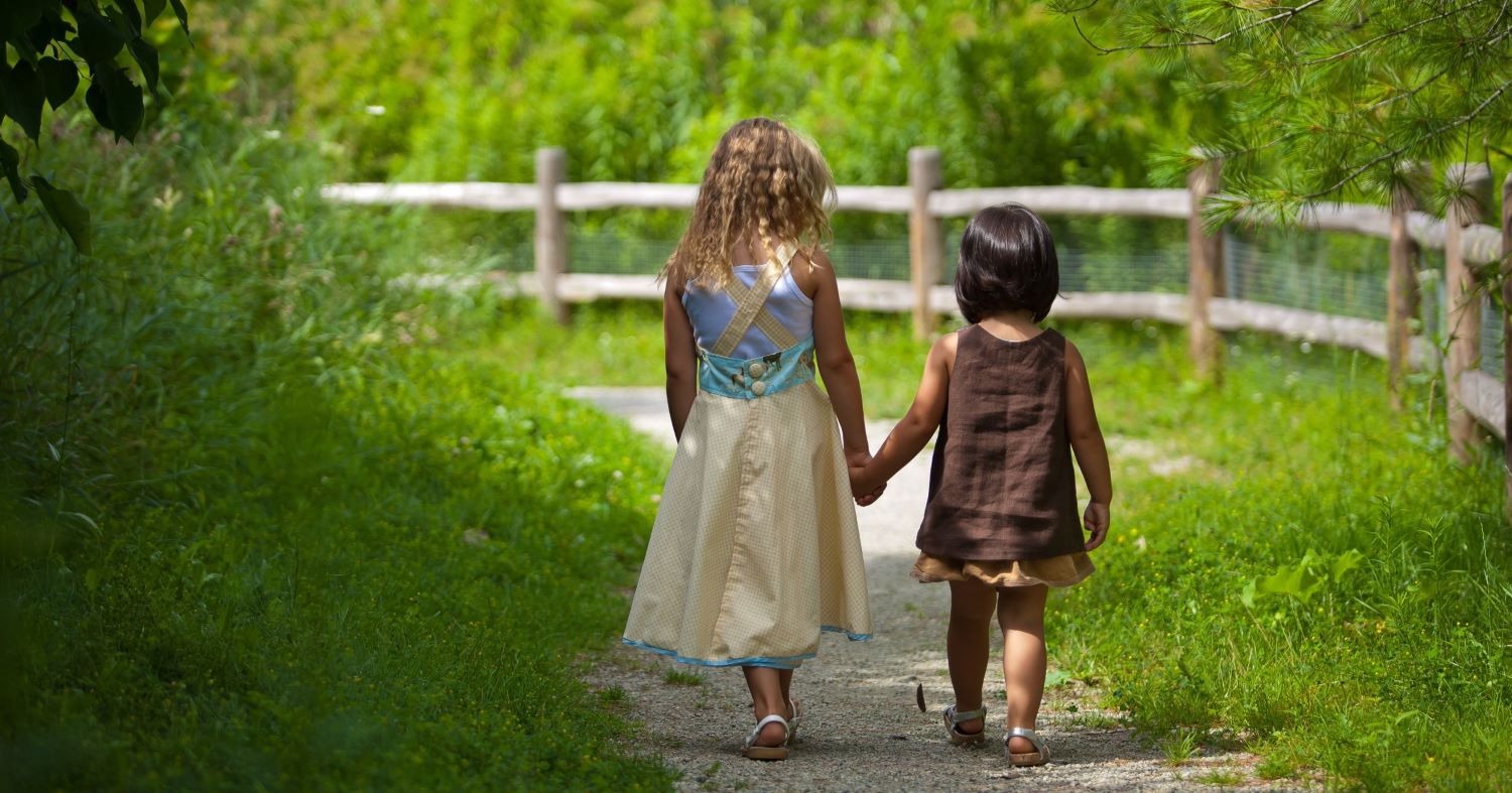 Two kids walking in green space