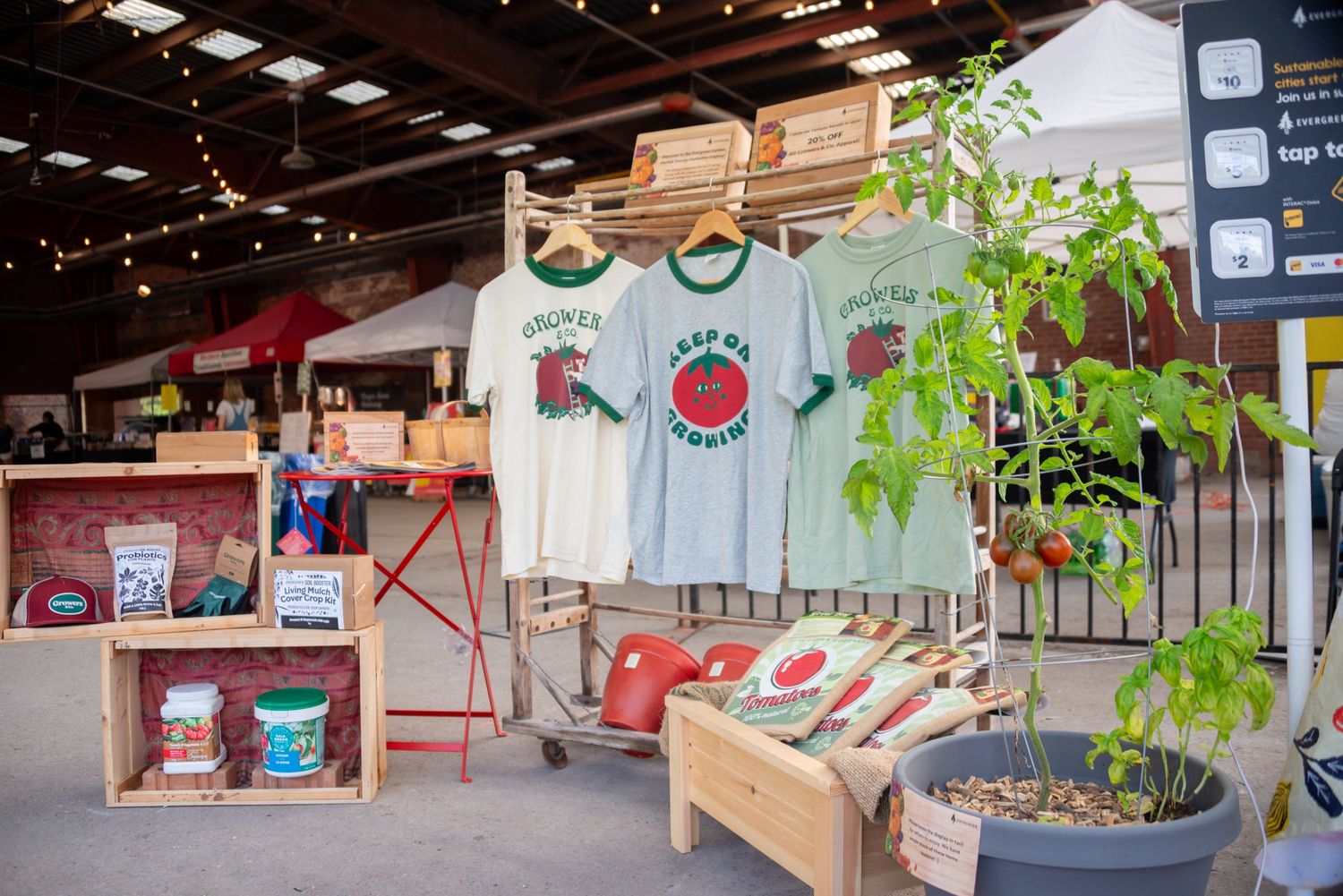 A variety of gardening products and tomato-inspired t-shirts on display at the farmers market