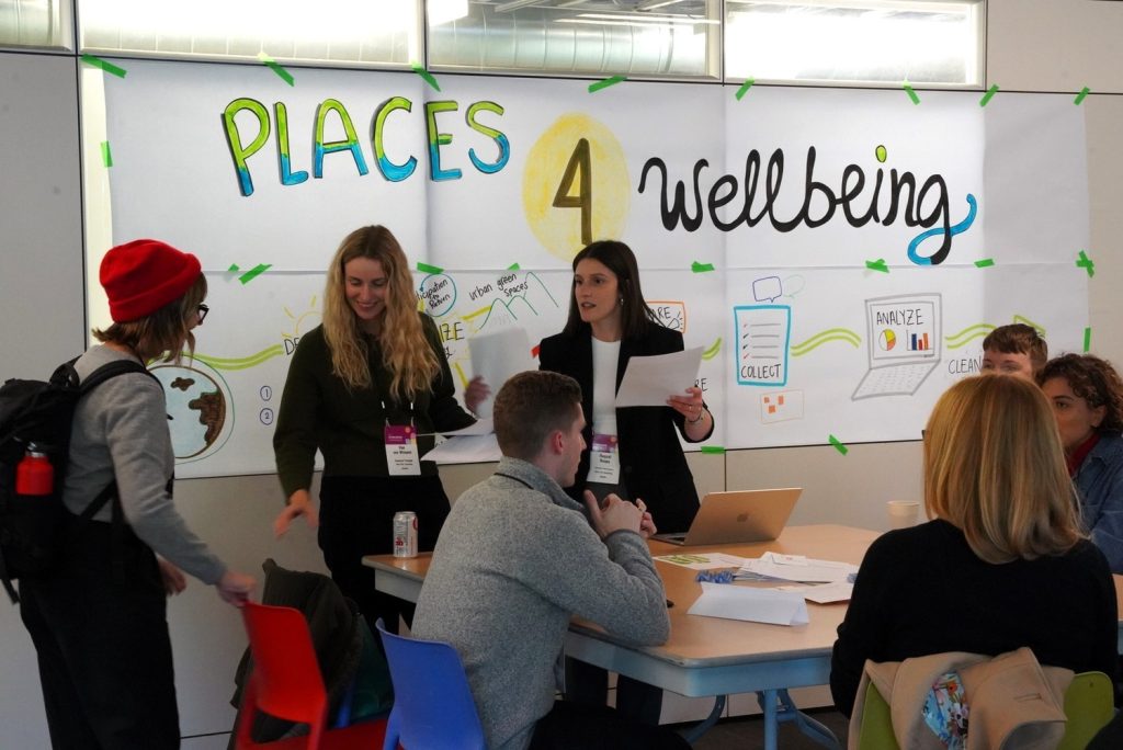 Deux conférencière de Davis Pier présente leur outil de mesure Place4wellbeing à un groupe de participants assis à une table