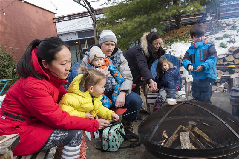 Family sat around camp fire roasting marshmallows