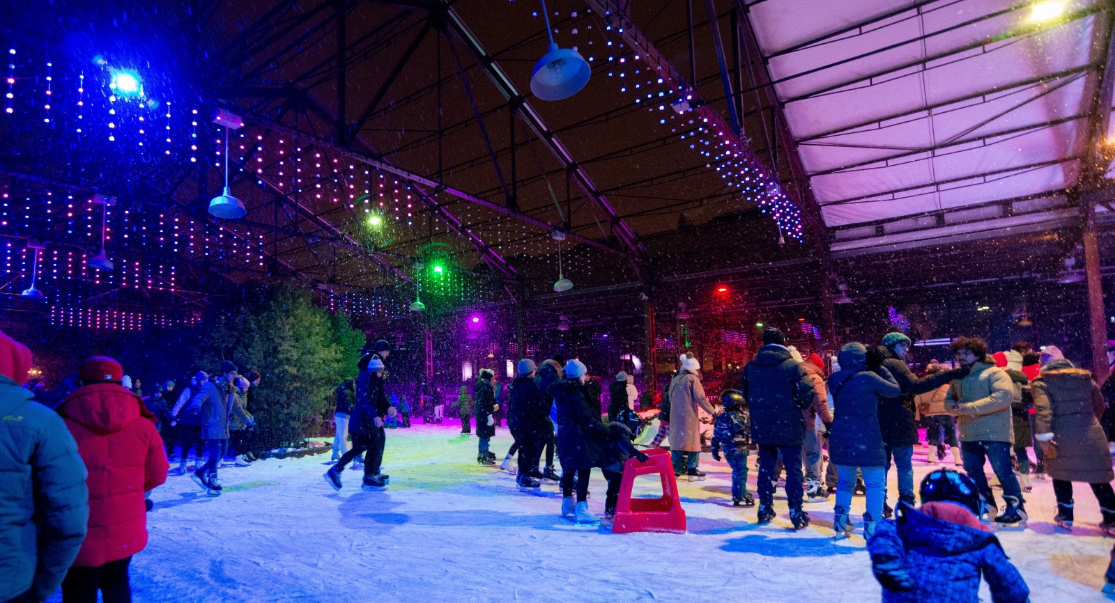 People skating outdoors, at night, in the snow.
