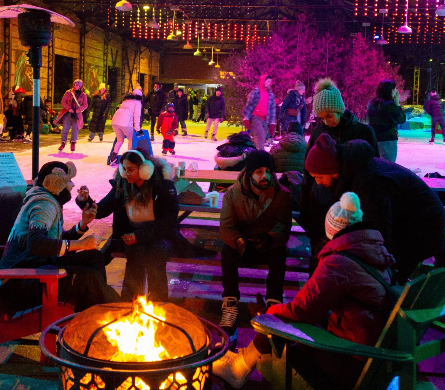 People cooking s'mores on the firepit beside the outdoor skating rink