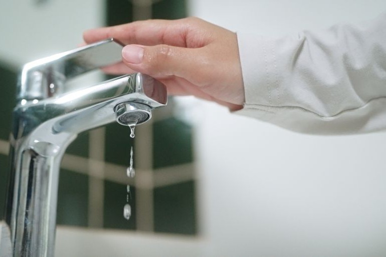 hand closing a running water tap