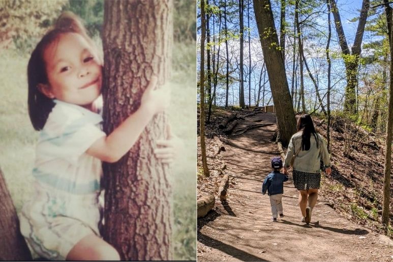 young kid sitting on a tree next to that person as an adult walking on a trail