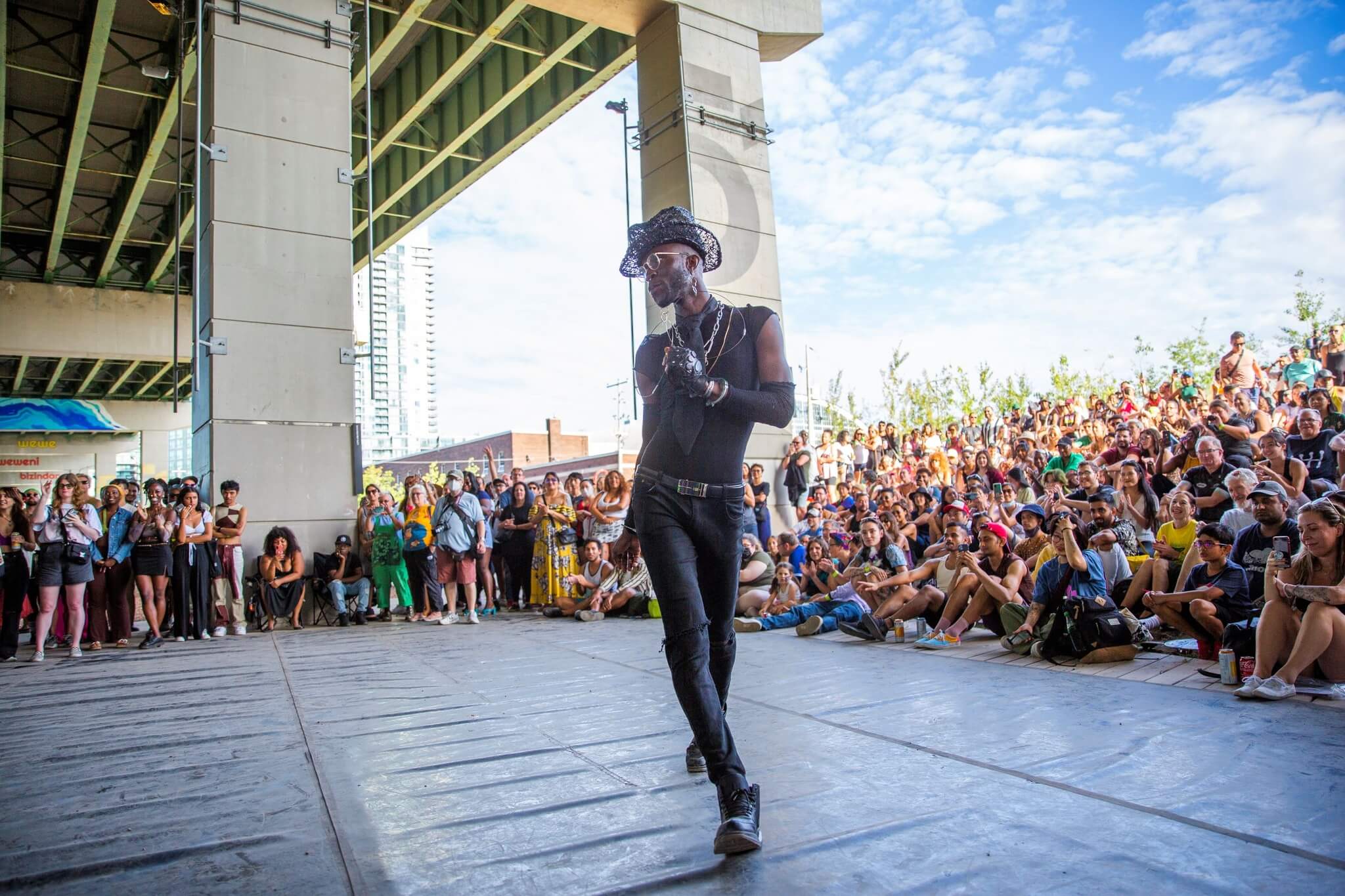 Man puts on performance surrounded by large crowd at Bentway in Toronto, underneath Gardiner Expressway