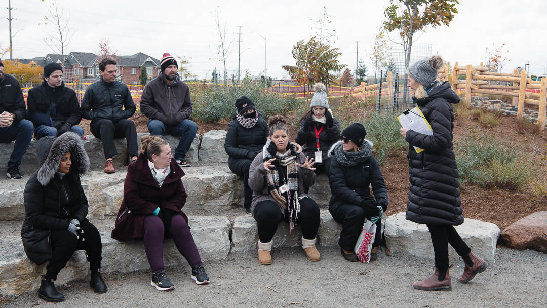 School teachers sit outside around an outdoor classroom during a professional development session.