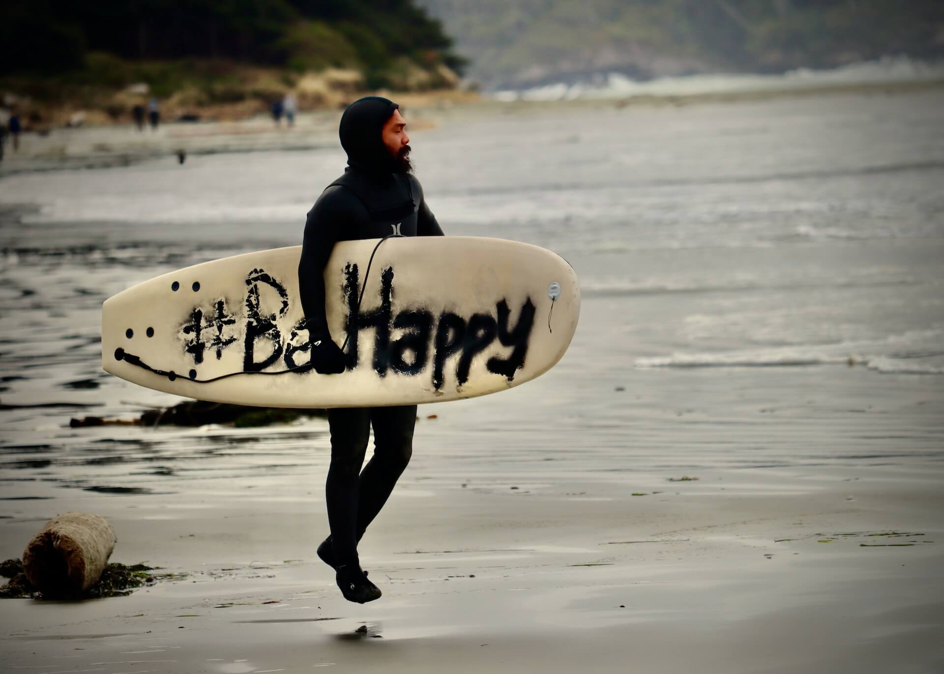 Person in wetsuite holding surfboard on the beacg