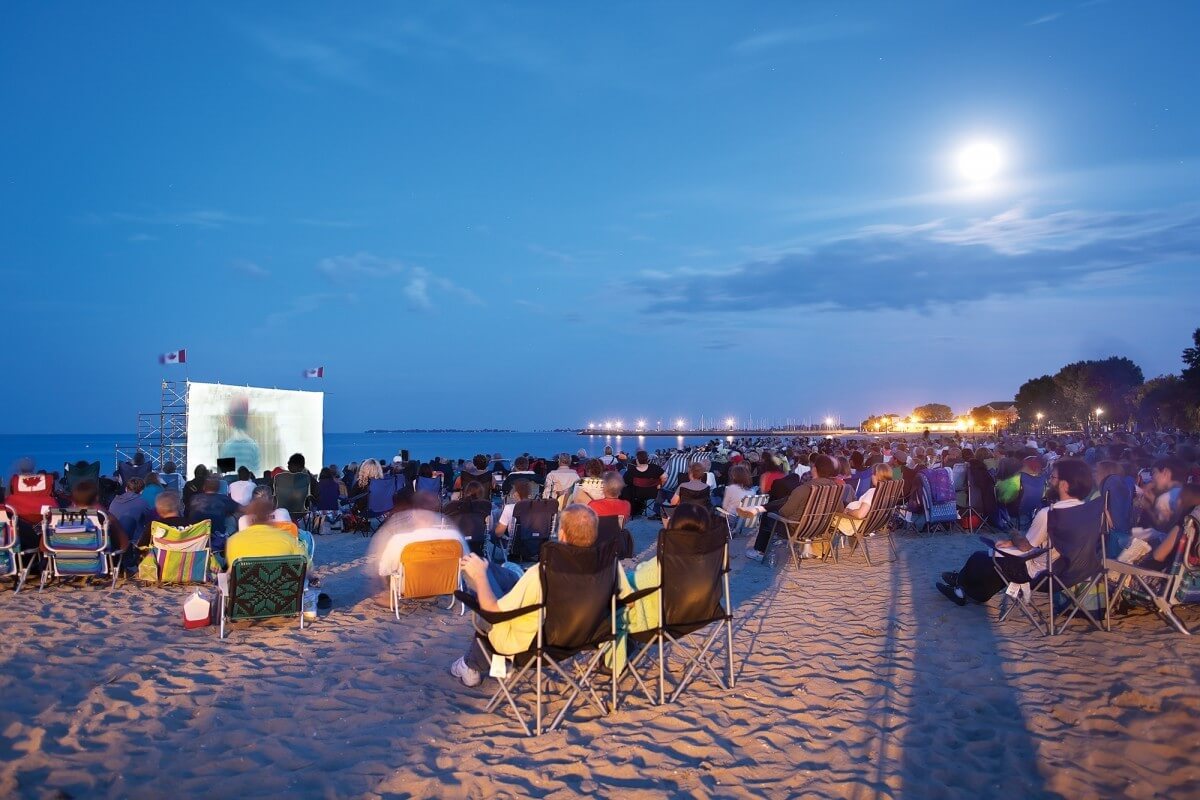 Lots of people on the beach at night for a festival. Beach lit up.