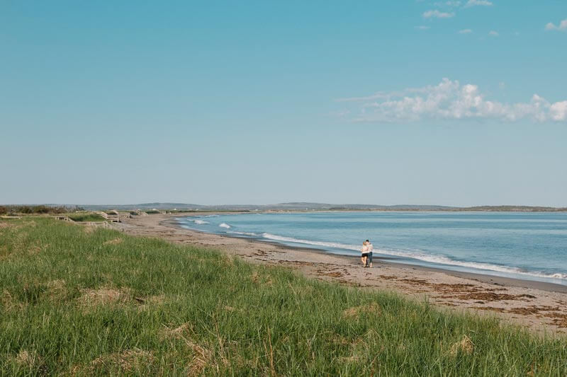 coastal beach with people walking on the sand next to water