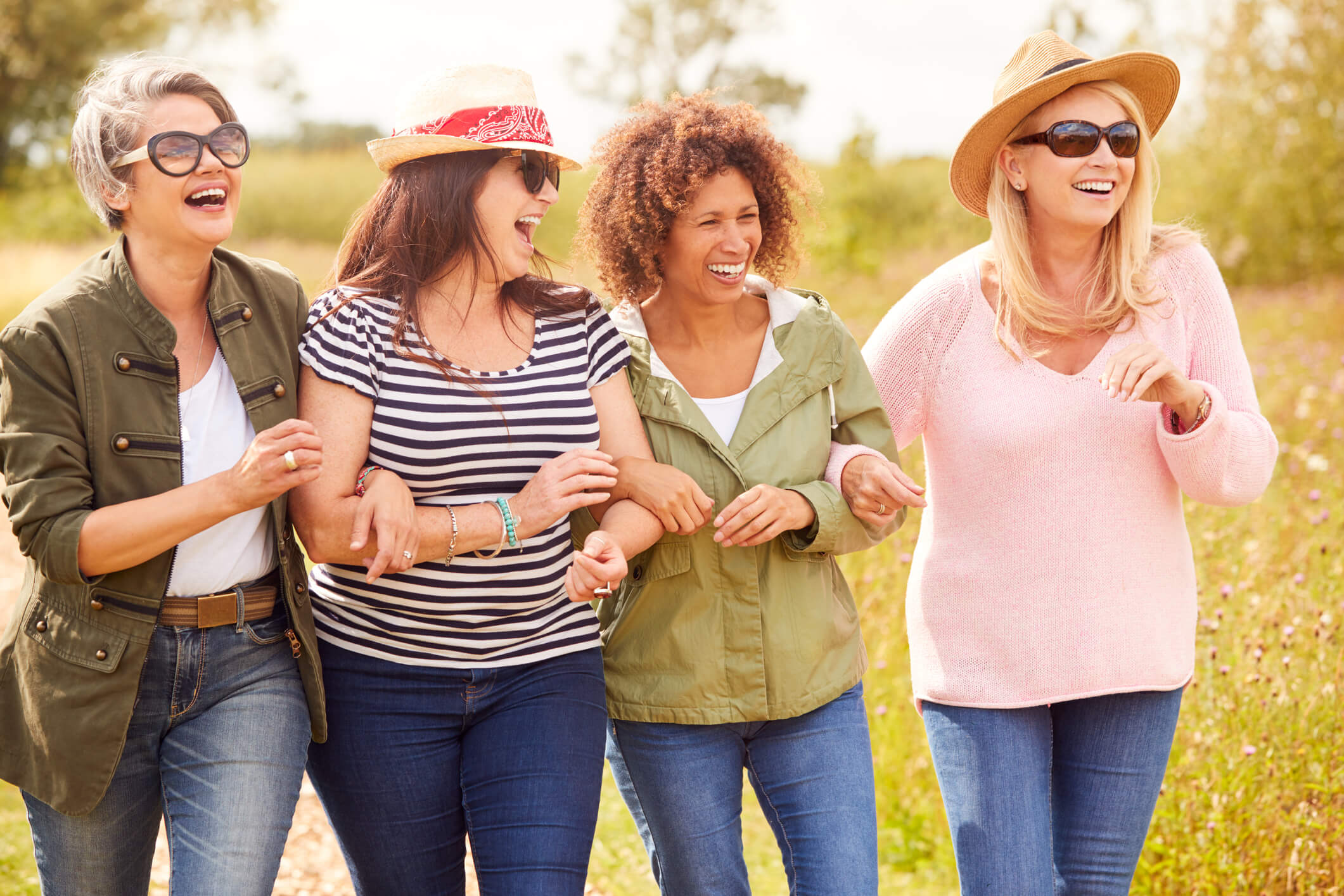 Group of four women walk together smiling and happy