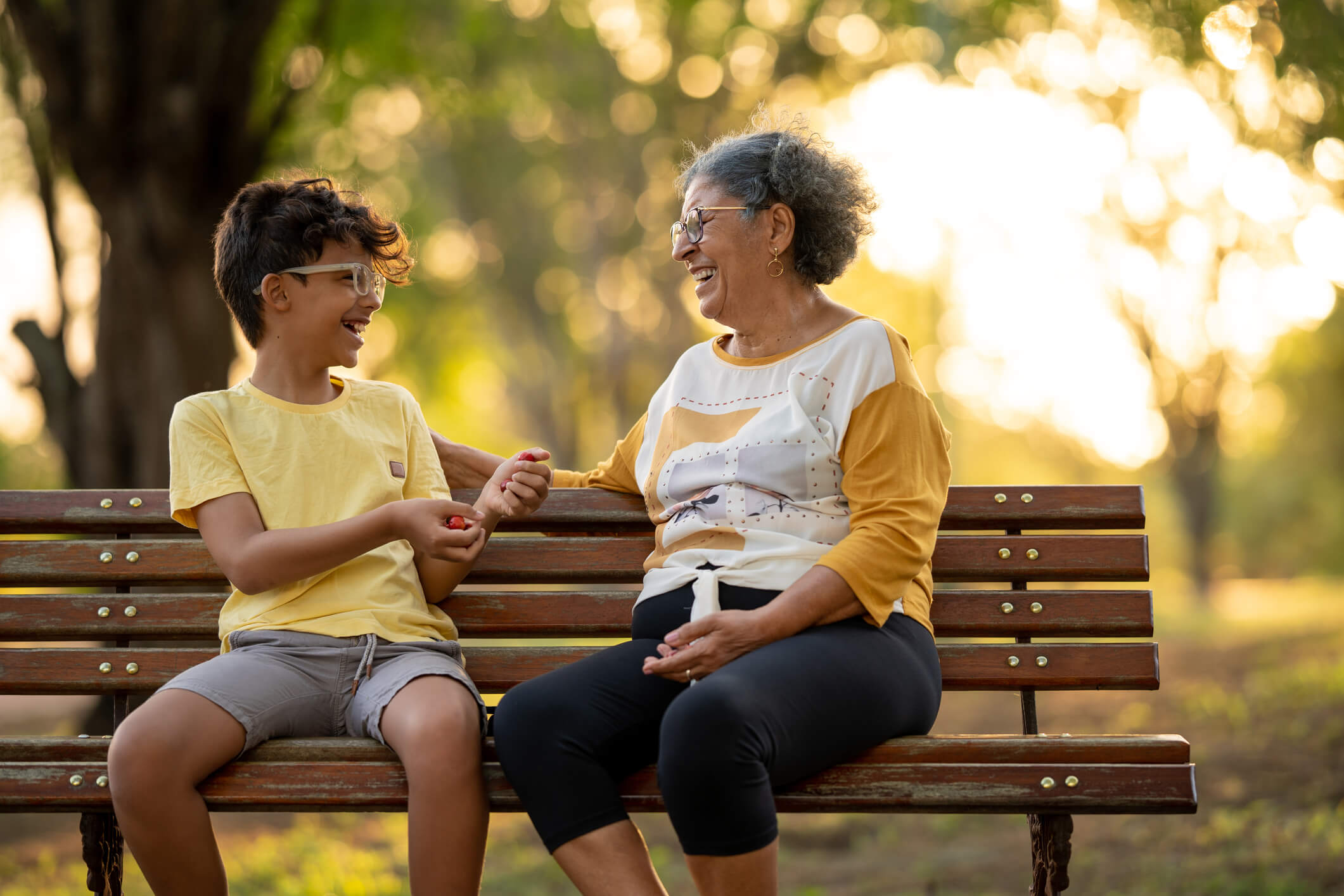 Adult and child sit on a park bench