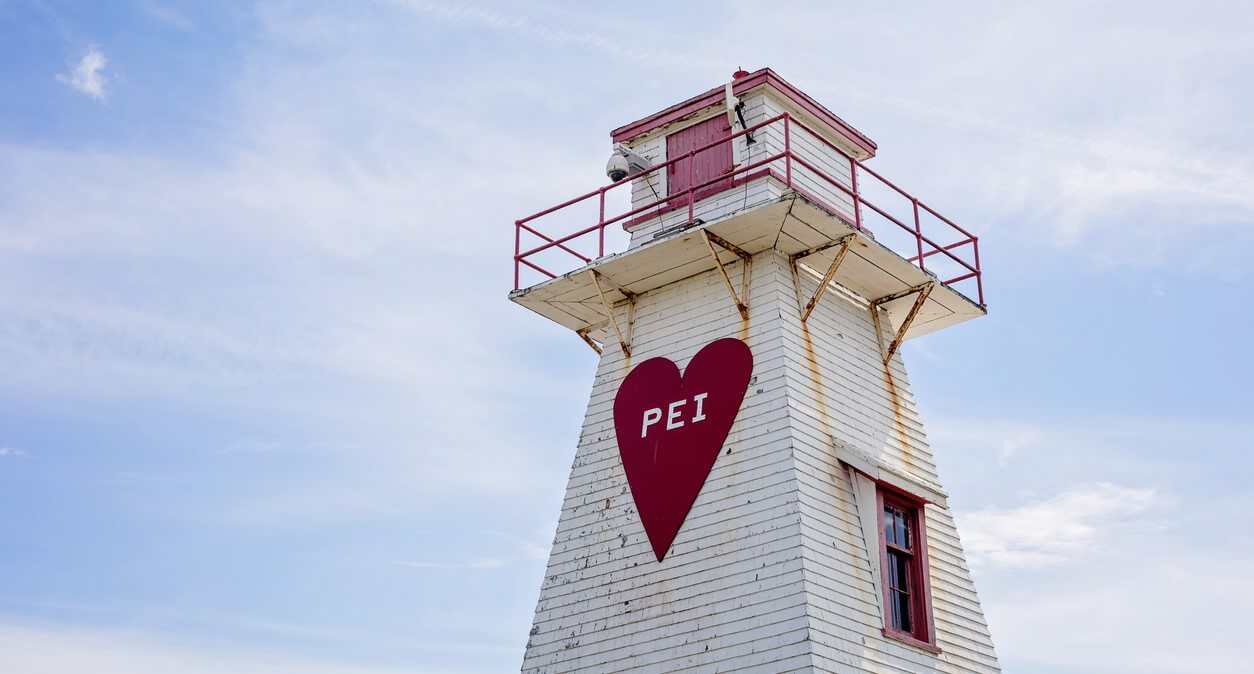 A lighthouse with a large red heart on it with with the letters PEI on the heart