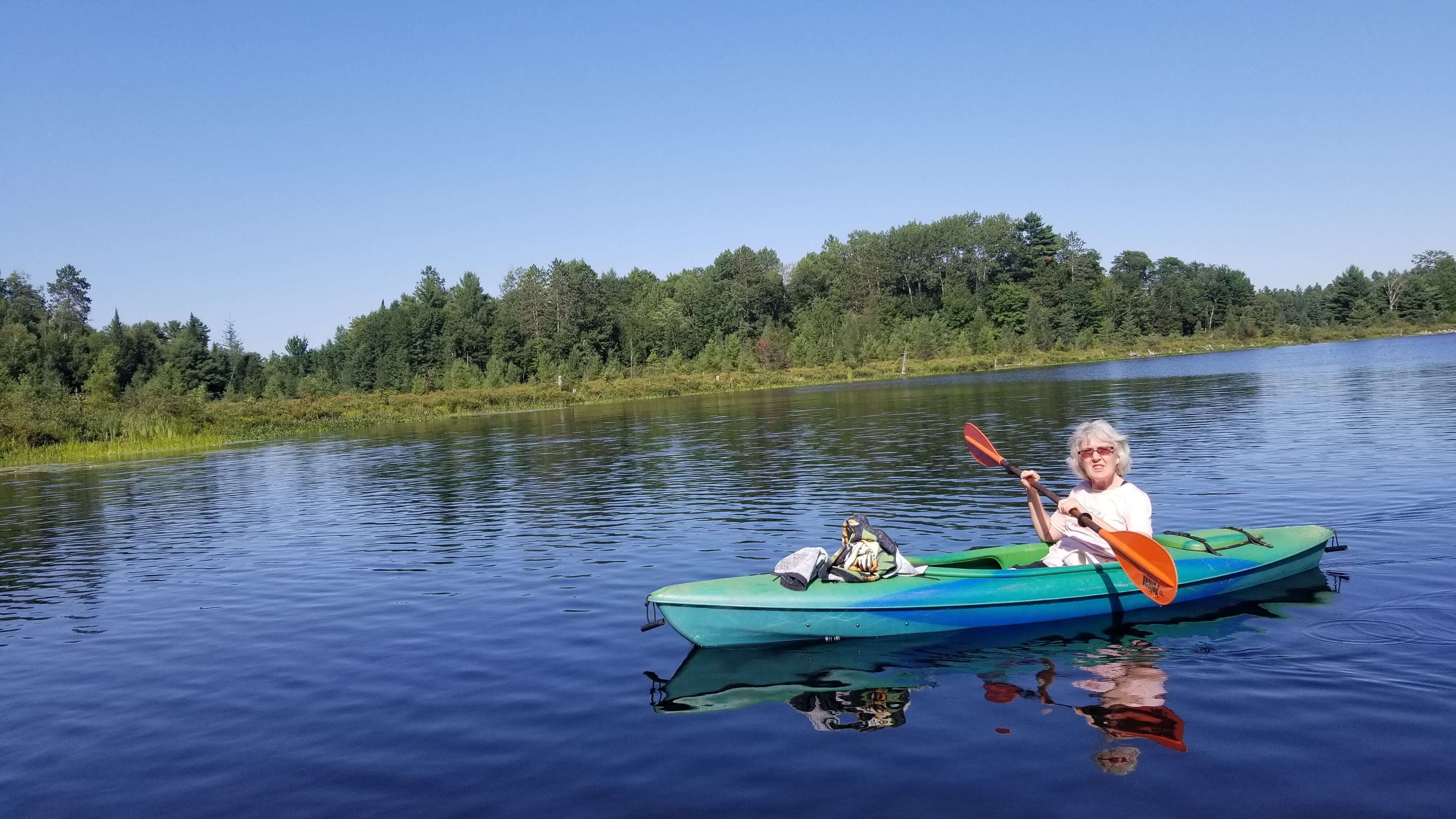 Person in canoe on the water with trees in the background
